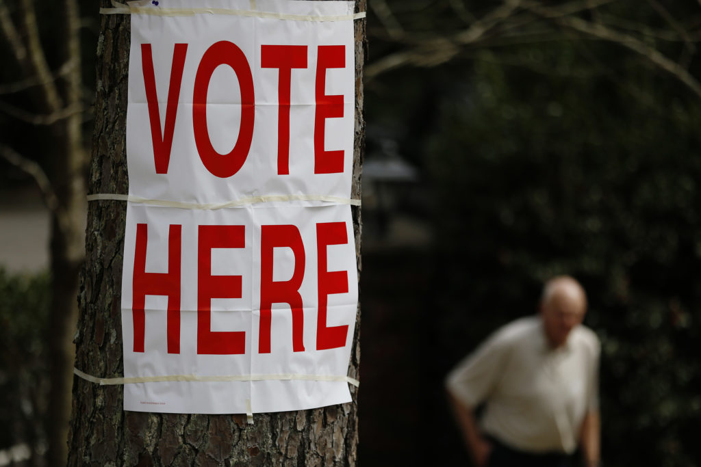 A voter walks by a "vote here" sign after he cast his ballot in Alabama's primary at a polling site, Tuesday, March 1, 2016, in Birmingham, Ala. (AP Photo/Brynn Anderson)